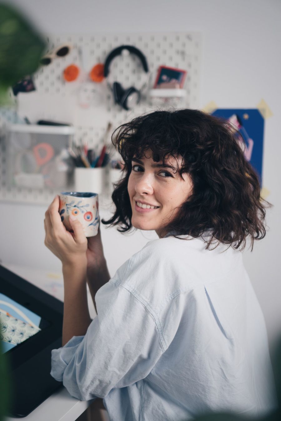 Adriana at her studio desk with a hand-painted mug